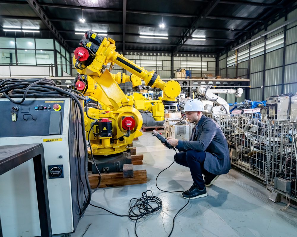Manufacturing engineer on clean factory floor reviewing data near robotic equipment