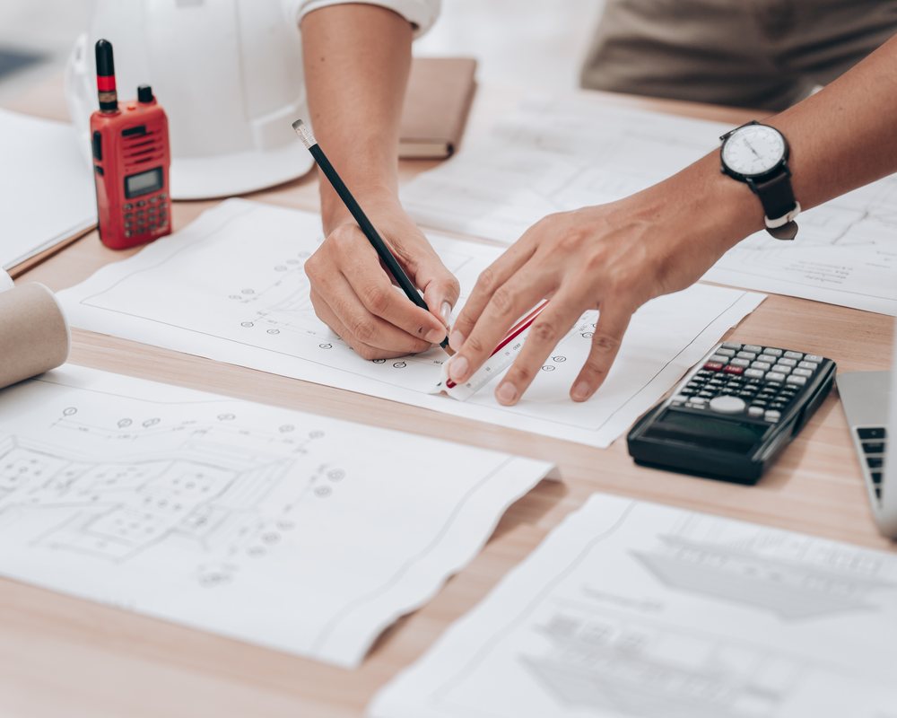 Structural engineer with rolled blueprints and CAD screen, focused craft of engineering work