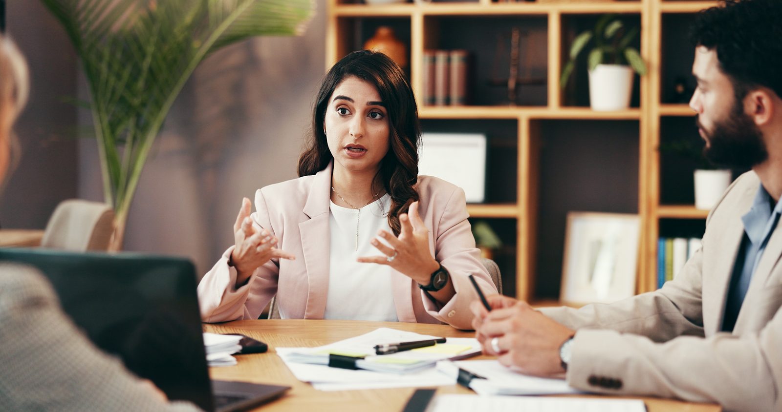 A 3i People recruiter coaching a candidate across a modern conference table — the advocate side of the table
